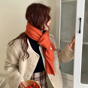 Elegante sciarpa in maglia arancione da donna in un caldo ambiente invernale.