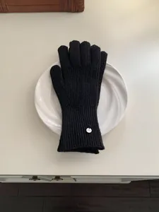 Elegant black knitted wool gloves with circular metal logo tag for women winter warmth