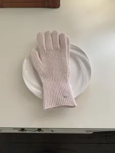 Soft pink knitted wool winter gloves for women featuring elegant metal brand tag accent