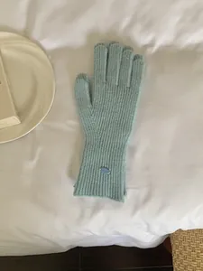 Close-up detail of soft light blue knitted winter gloves with small oval metal tag