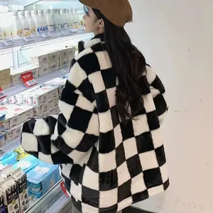 Detailansicht einer weichen, dicken schwarz-weiß karierten Plüschjacke an einer Person.