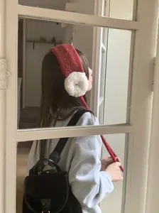 Nahaufnahme einer Frau mit rot-weißen Strick-Ohrenschützern mit Bändern für Winter