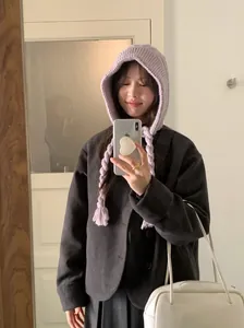 Young woman wearing a soft purple knitted hooded hat with braided ties in a mirror