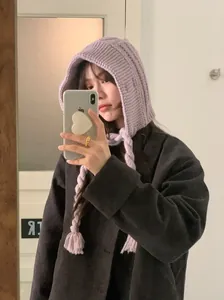 Asian model wearing a purple knitted hooded hat with long braided ties in a selfie.