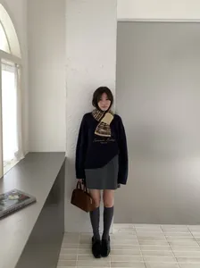 Mannequin asiatique portant une écharpe en tricot Fair Isle rétro dans un décor épuré.