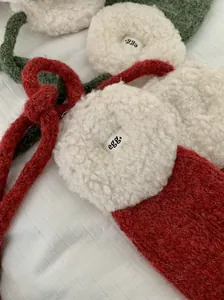 Detailaufnahme von weichen Plüsch-Ohrenschützern mit roten Strickbändern und Logo