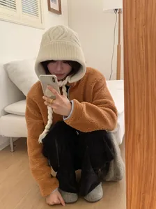 Mirror selfie of a cozy beige knitted Leifeng hat with long ear protection straps.