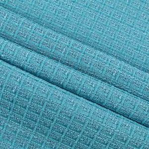 Gros plan sur un tissu en tweed turquoise avec un motif à carreaux texturé pour la mode d'été