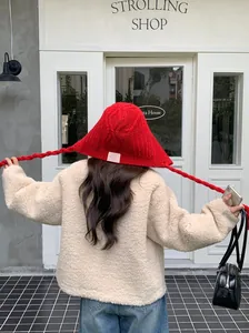 Back view of a red knitted winter hat with ear flaps and long braided ties