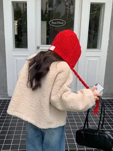 Back view of a woman wearing a vibrant red knitted beanie with braided earflaps