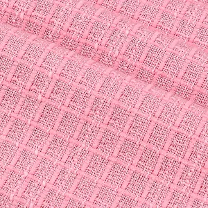 Vue macro détaillée montrant le tissage et la texture du tissu en tweed rose pour vêtements