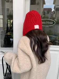 Close-up back view of a vibrant red knitted trapper hat with warm protective ear flaps