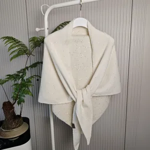 Detailopname van een crème wollen sjaal met subtiele glinsterende lovertjes.