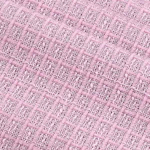 Gros plan sur un tissu en tweed bouclé rose délicat avec des fils pailletés argentés brillants.
