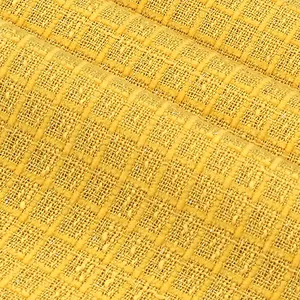 Vue macro d'un tissu en tweed jaune montrant la texture quadrillée et les détails du polyester