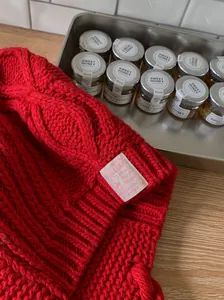 Close-up of a red cable-knit Lei Feng winter hat with a decorative brand tag.