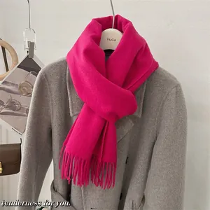 Gros plan d'une écharpe en laine fuchsia 100% avec franges sur un manteau gris