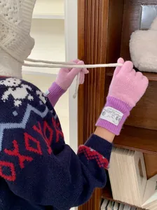 Gros plan de gants en laine tricotés rose et violet portés dans un cadre chaleureux.