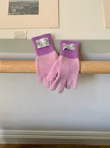 Détail de gants en laine tricotés bicolores rose et violet avec étiquette en tissu