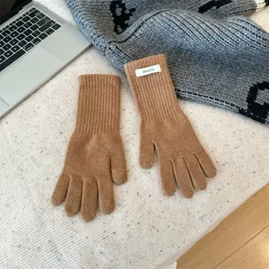 Detailed close-up of brown 100% merino wool knitted winter gloves with material tag