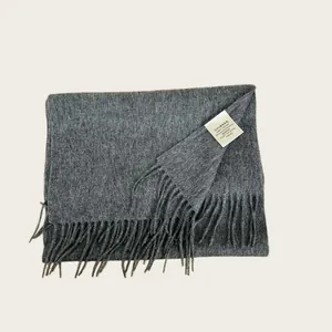 Detailed macro shot of a gray 100% Australian wool scarf with fringe and care label
