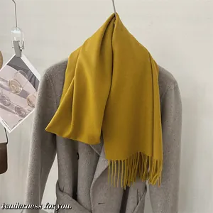Gros plan détaillé d'une écharpe douce en laine 100 % jaune moutarde avec des franges