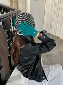Detailansicht von grünen Wollmisch-Strickhandschuhen mit einem kleinen Metallschild-Akzent