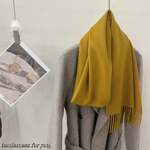Écharpe douce en laine jaune moutarde avec franges drapée sur un manteau gris élégant
