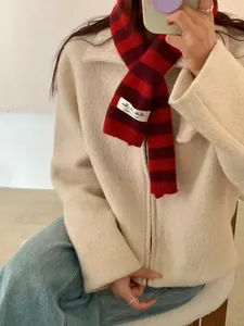 Close-up of a red striped wool blend scarf with a cross-through hole design on a model.