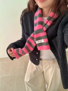 Detailed view of the pink and gray striped knitted wool scarf worn over a dark cardigan.