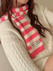 Detailed macro shot of a pink and white striped wool scarf featuring a woven brand label.