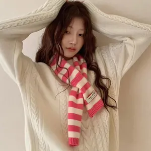 Model wearing a pink and white striped wool blend scarf with a perforated winter design