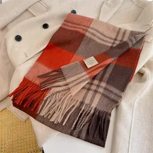 Close-up of 100% Australian wool scarf in pumpkin brown and orange plaid pattern with fringe.