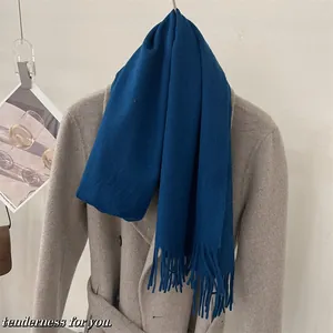 Gros plan d'une écharpe en laine bleu lac avec franges sur un manteau gris