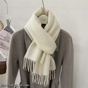 Détail d'une écharpe en laine crème douce avec des franges sur un manteau gris