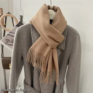 Écharpe douce 100% laine de couleur camel avec franges sur un détail de manteau