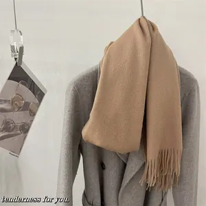 Détail d'une écharpe en pure laine de couleur chameau drapée sur un manteau d'hiver gris
