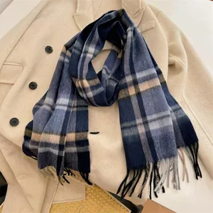 Close-up of blue plaid wool scarf with long fringes draped on a beige coat