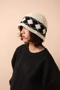 Detail view of a retro Nordic knit wool bucket hat in cream and black on a model