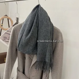 Vue détaillée d'une écharpe en laine grise de haute qualité avec franges sur un manteau