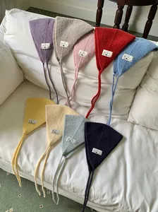 Variety of colorful vintage knitted ear warmers with tie strings on a white sofa