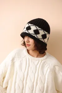 Detail view of the Nordic diamond knit pattern on a thick black and white wool beanie hat