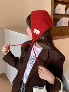 Side view of a vintage red knitted ear warmer with a wool blended patch and ties