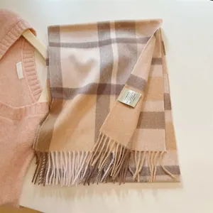 Macro detail of a vintage pumpkin brown plaid 100% wool scarf with soft tassels.