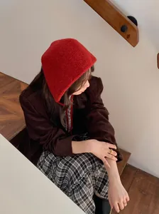 Vintage red knitted ear-warming hood shown on model in a cozy staircase lifestyle setting