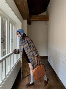 Asian female model wearing a retro blue knit ear warmer in a vintage hallway setting.