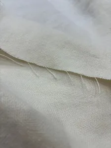 Close-up detail of natural beige linen cotton fabric showing textured weave and raw edge.