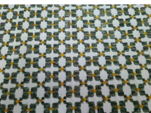 Close-up macro view of vintage green and yellow jacquard fabric with geometric patterns.