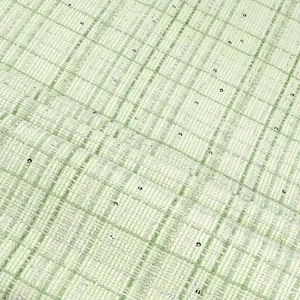 Close-up of green plaid tweed fabric with shimmering silver sequins for elegant apparel