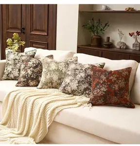 Détail de housses de coussin en jacquard floral vintage sur un canapé crème.